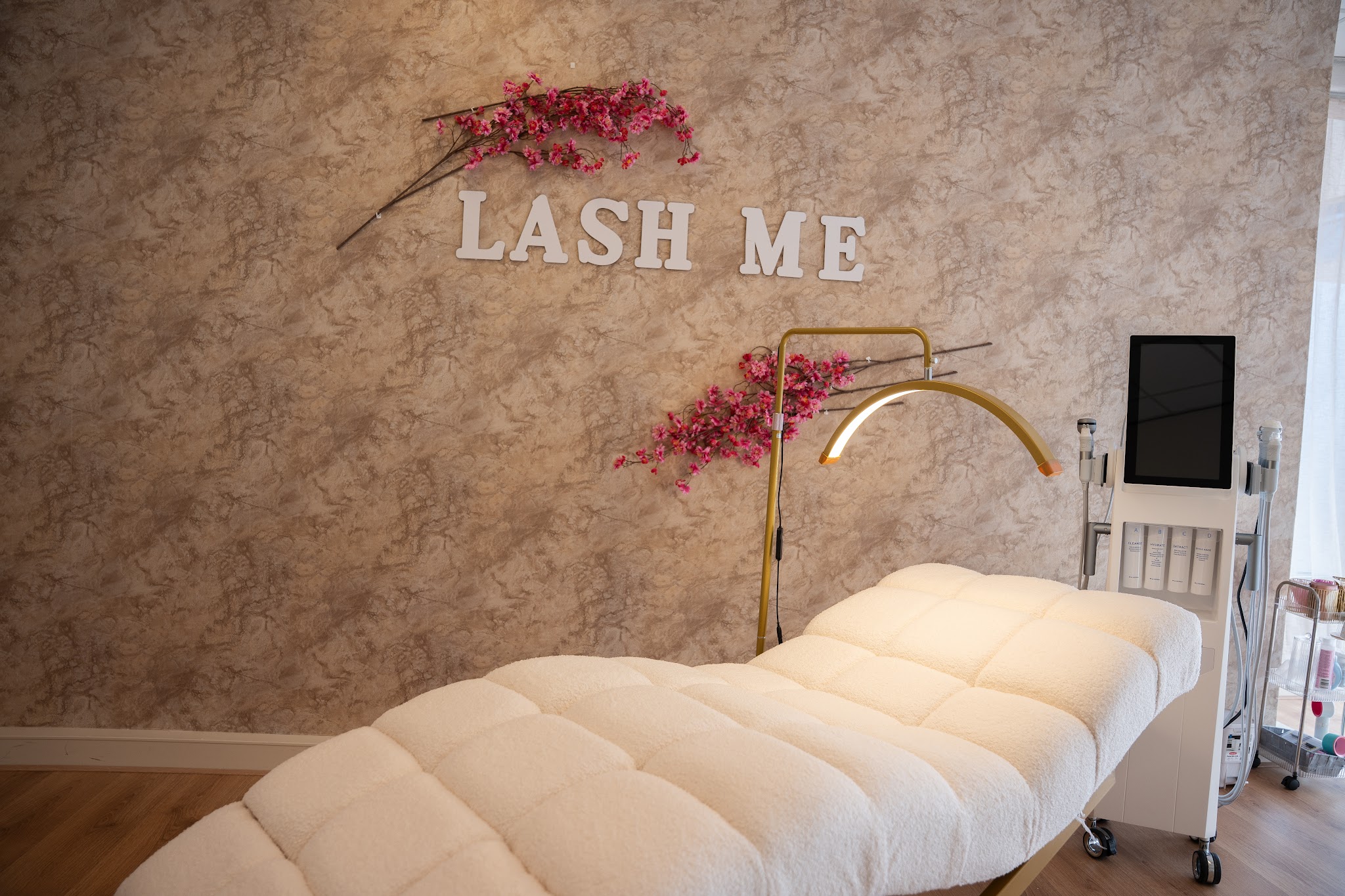 Behandelbed met bloemen en de wandtekst LASH ME in de salon